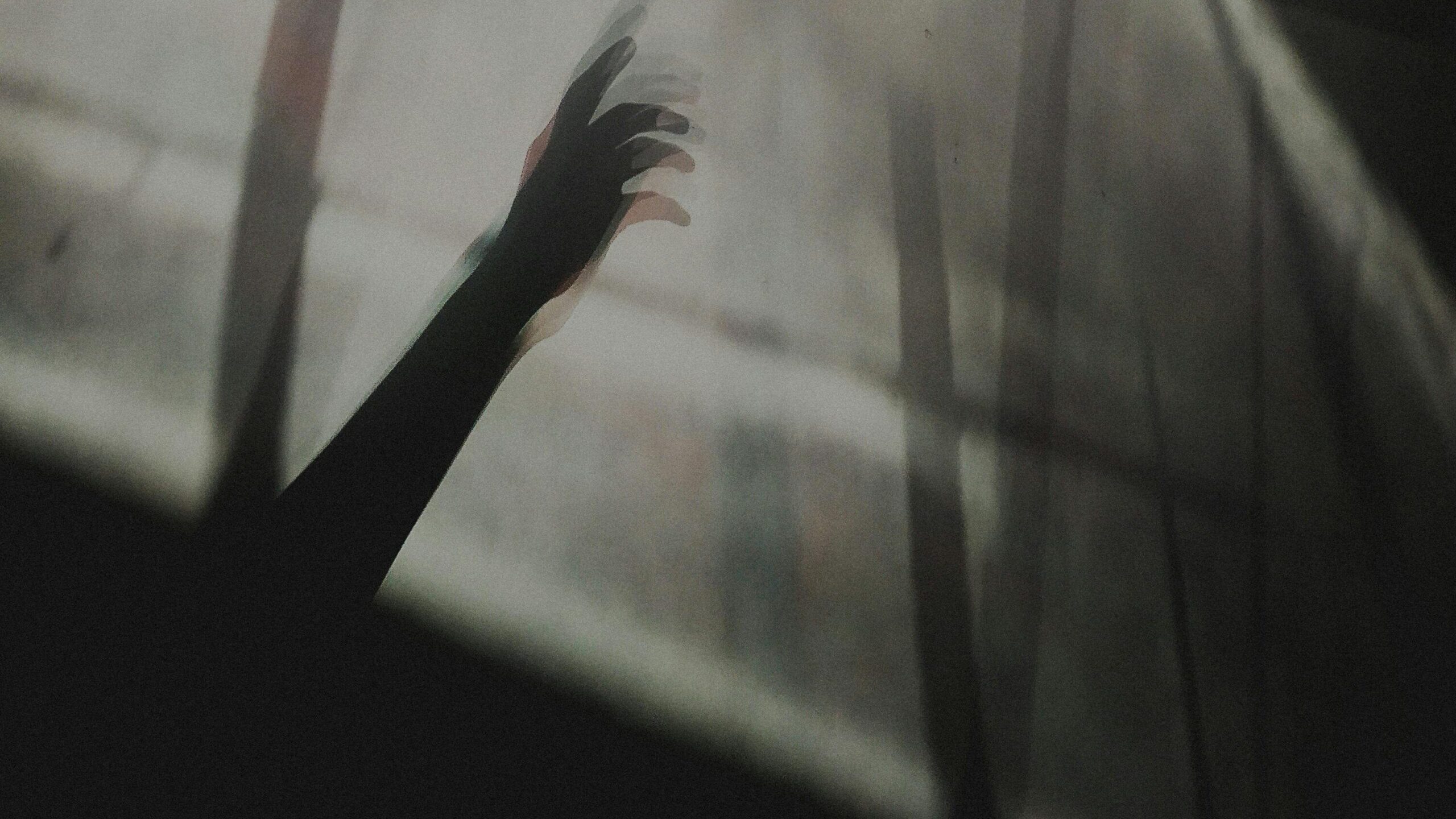 A shadow of a hand reaching through soft light diffused by fabric, creating a mysterious ambiance.