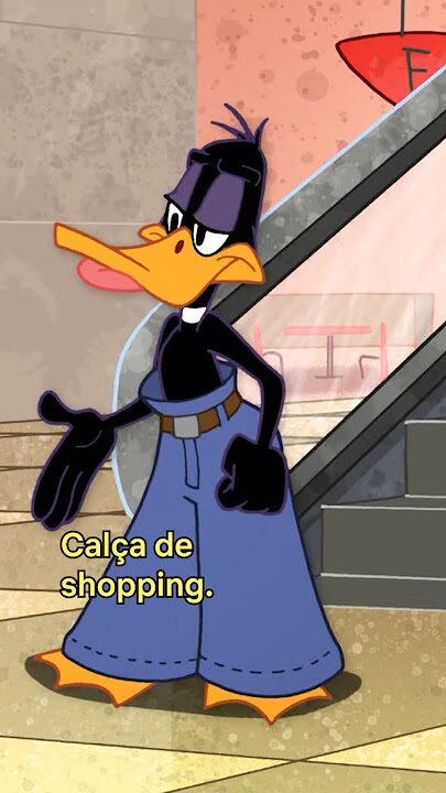 Desenho animado do personagem Patolino, do universo Looney Tunes, em frente a uma escada rolante. Ele está usando uma calça jeans larga de cintura alta, com cinto marrom, e aparece com expressão séria. Na parte inferior da imagem há a legenda em português: “Calça de shopping.”